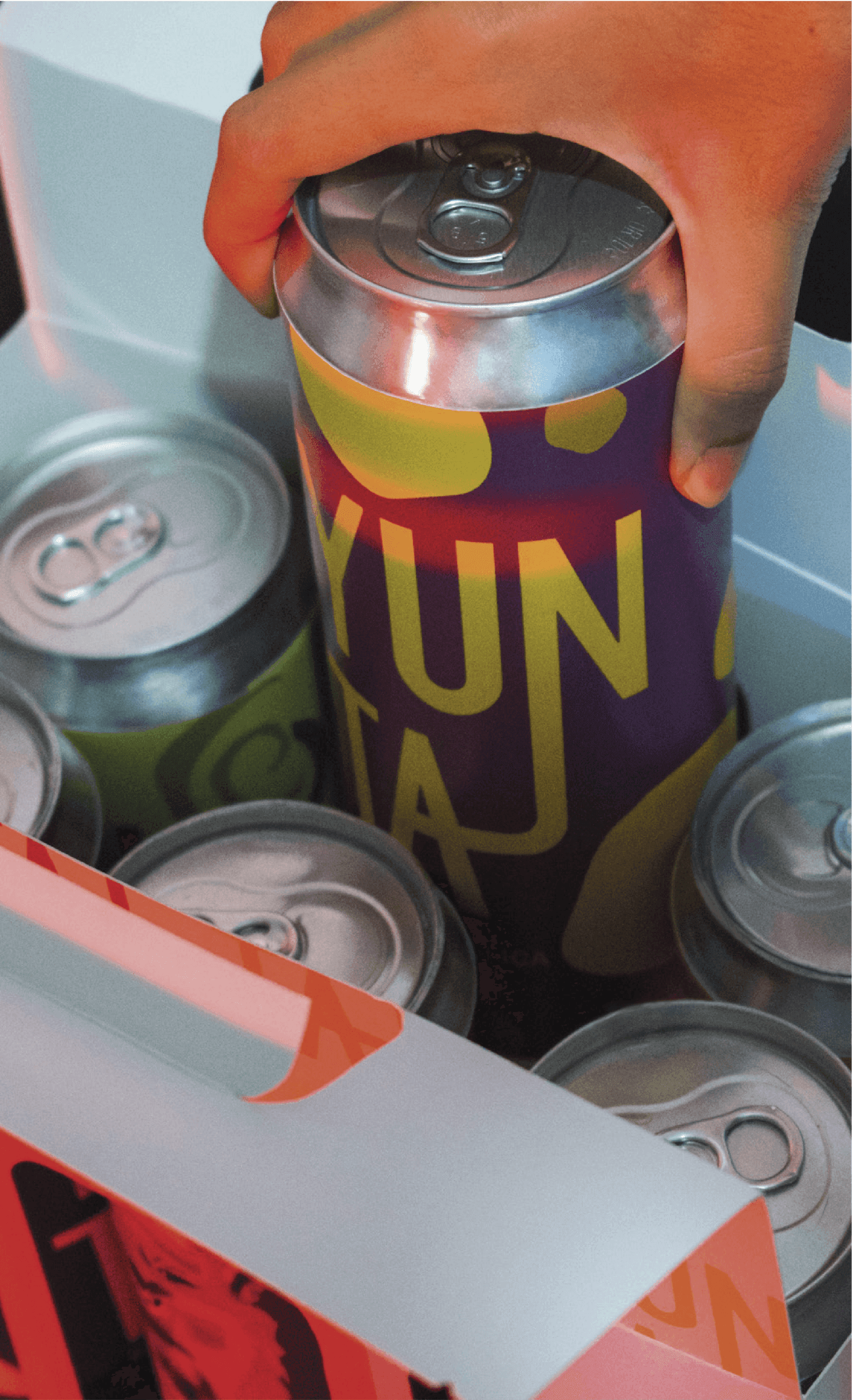 Una mano saca una lata Yunta de un cooler con hielo y otras latas sin etiqueta.
