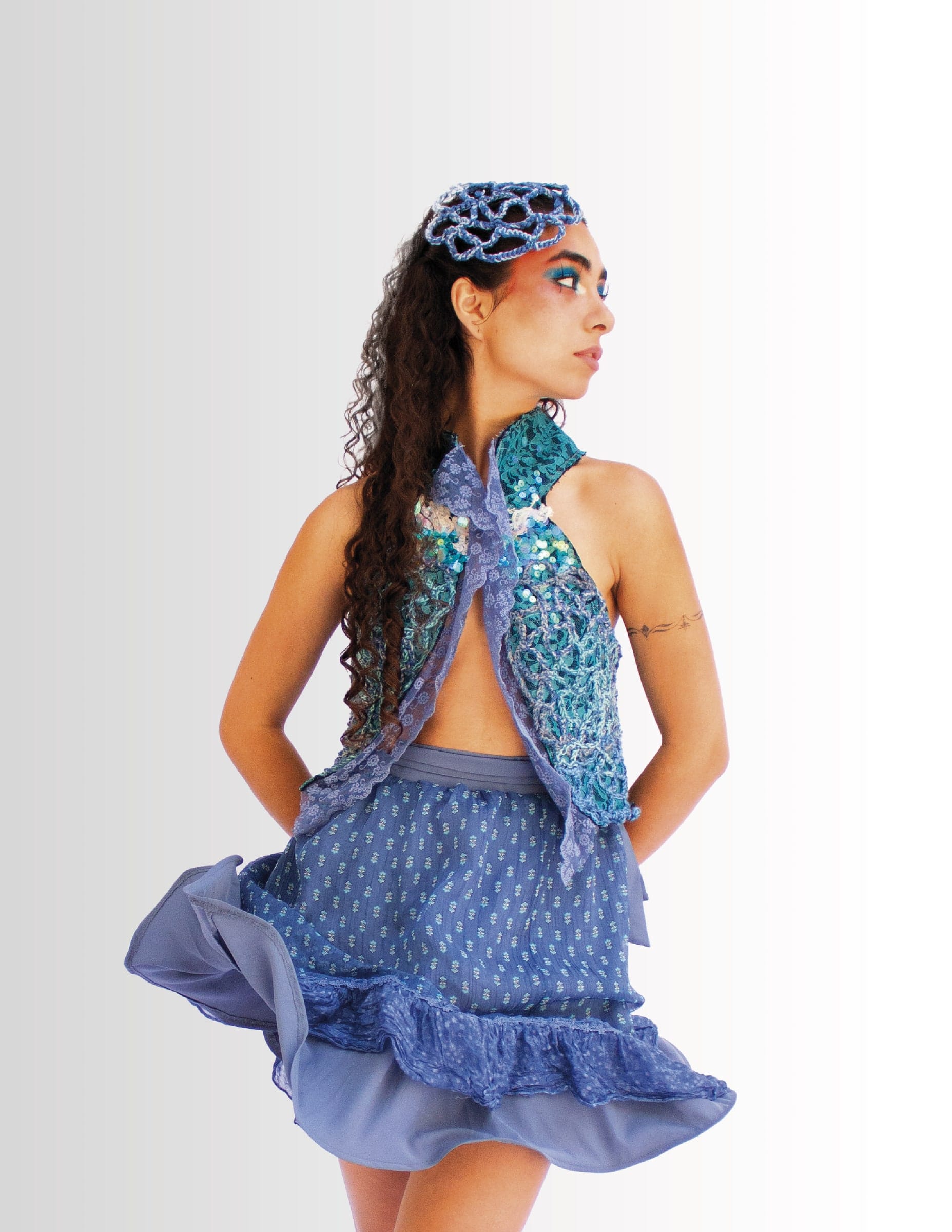 Modelo de espaldas con el conjunto turquesa y azul, con un tocado de crochet.