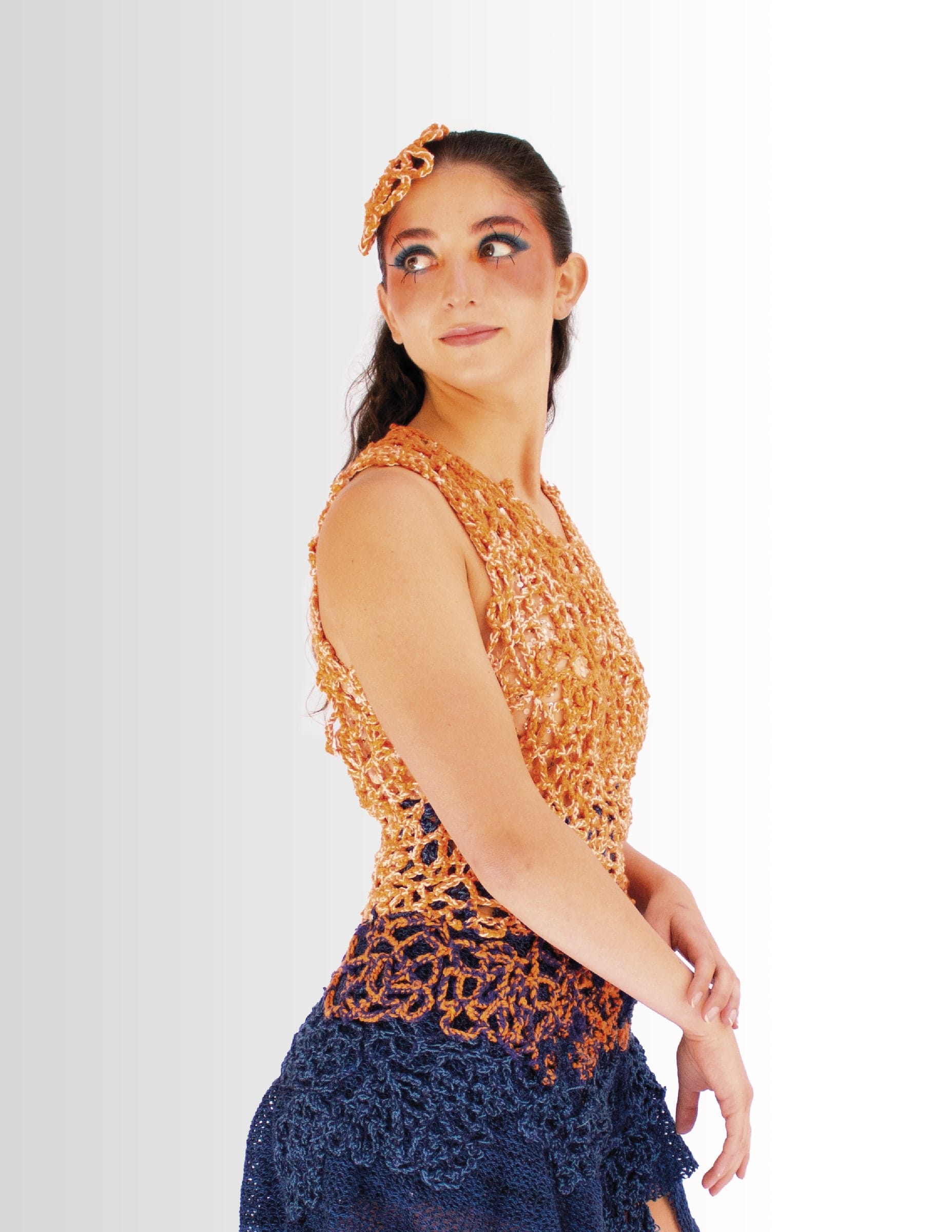 Modelo con top de crochet naranja y falda azul oscuro, de perfil.