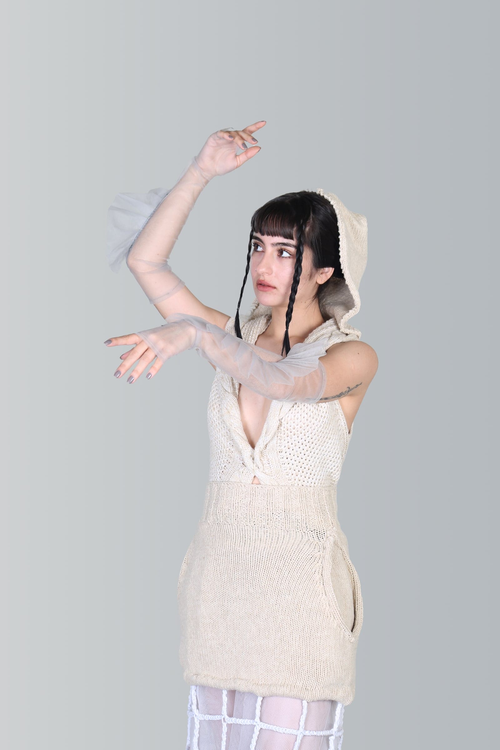 Modelo en estudio con vestido crudo y gasa, los brazos extendidos hacia arriba.