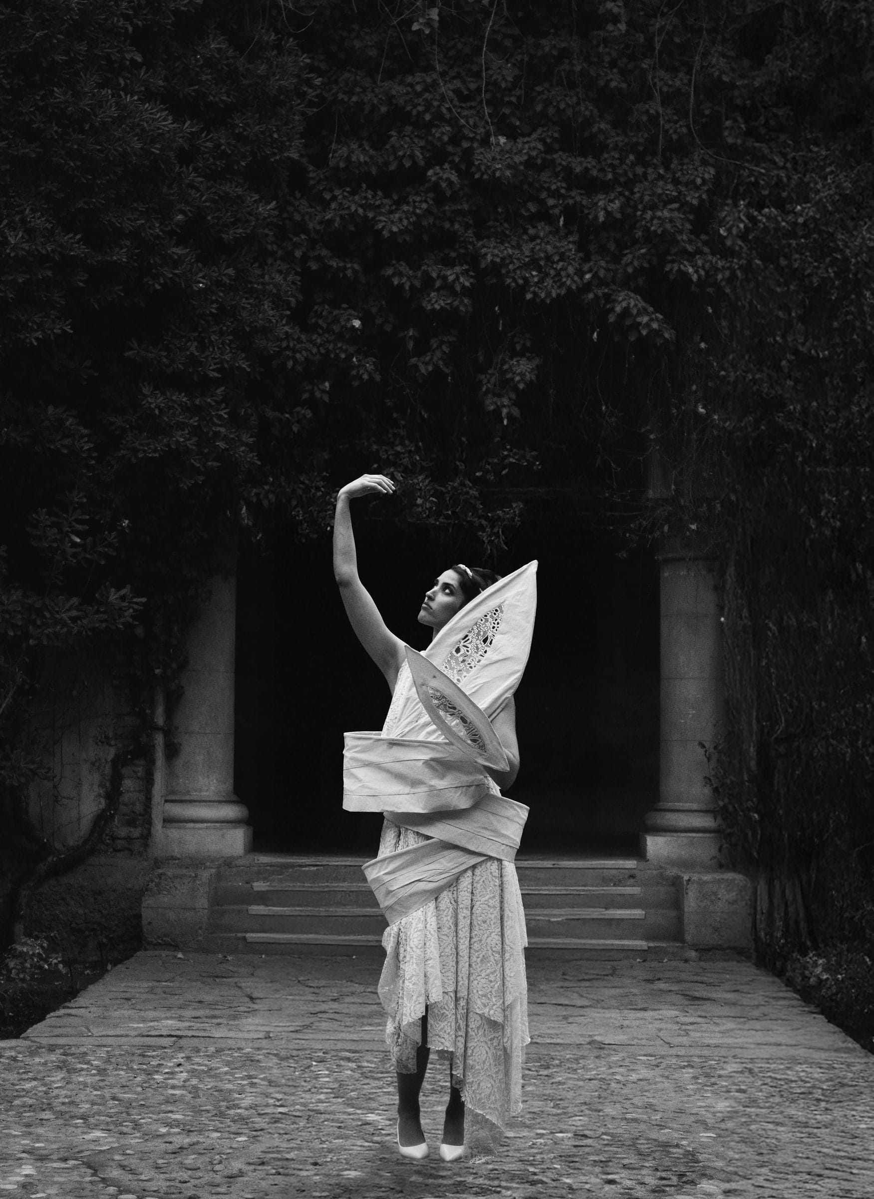 La misma serie en blanco y negro: la modelo al fondo de un corredor de columnas.