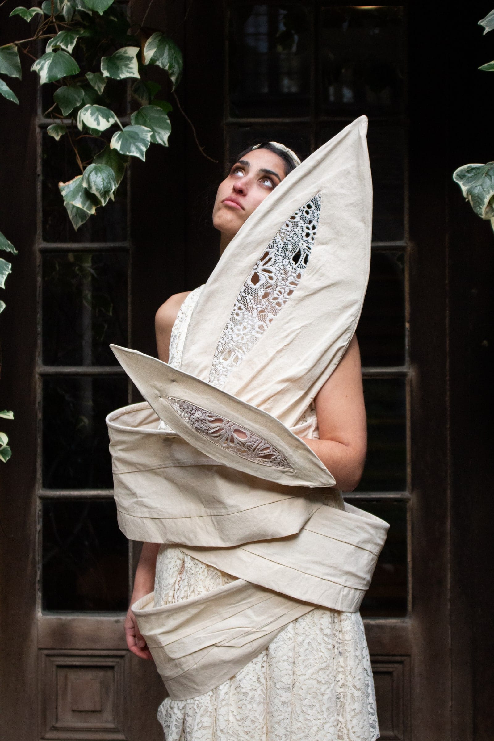 Modelo junto a una puerta antigua de madera, con la prenda de encaje y el cuello alzado.