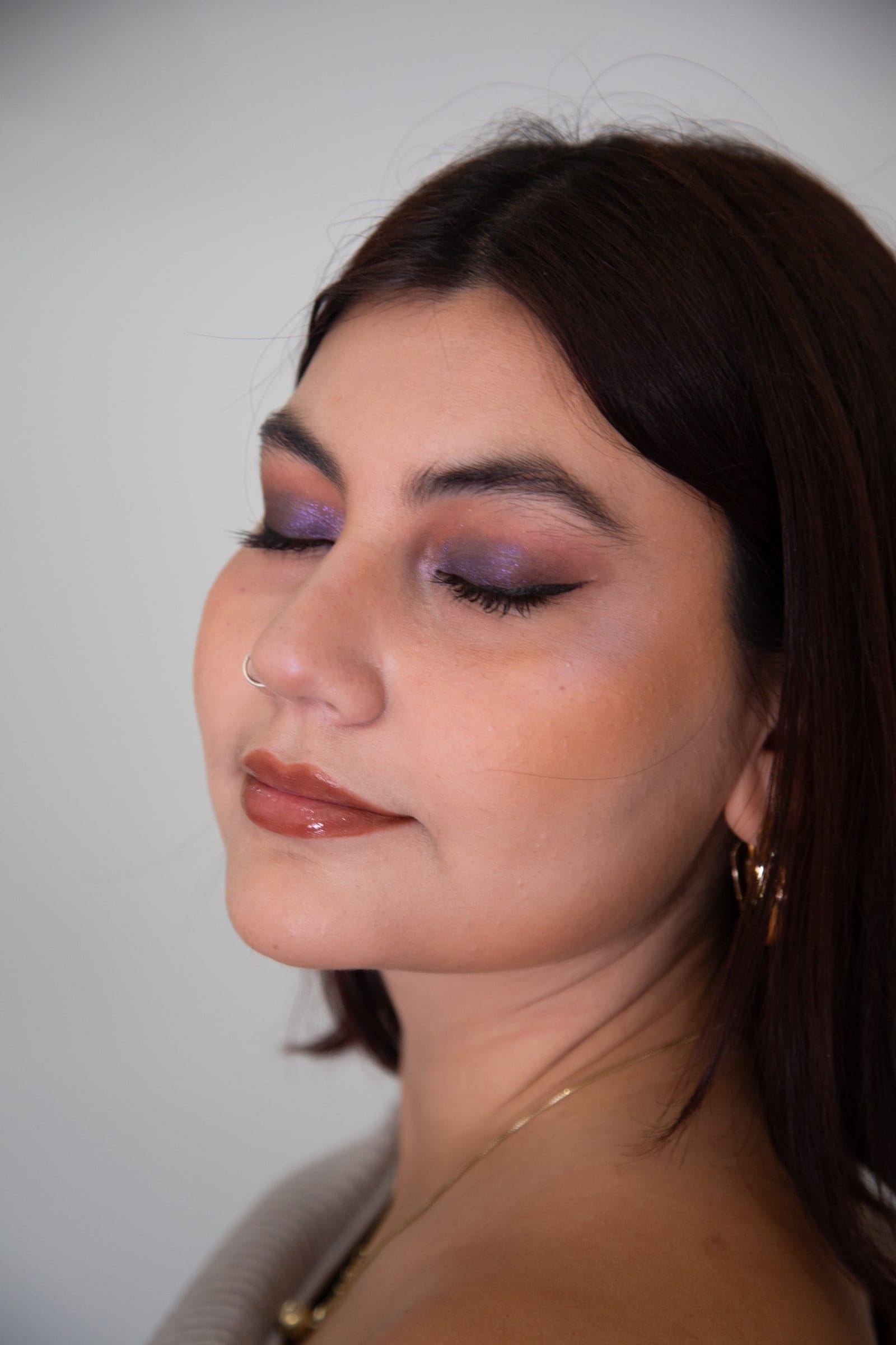 Retrato de maquillaje en primer plano, con los ojos bajos y la luz cayendo por un costado.