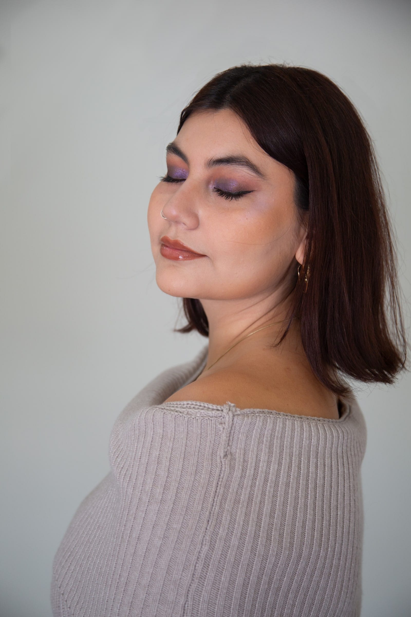Retrato de maquillaje: mujer de perfil tres cuartos con los ojos cerrados, sombras en tono vino.